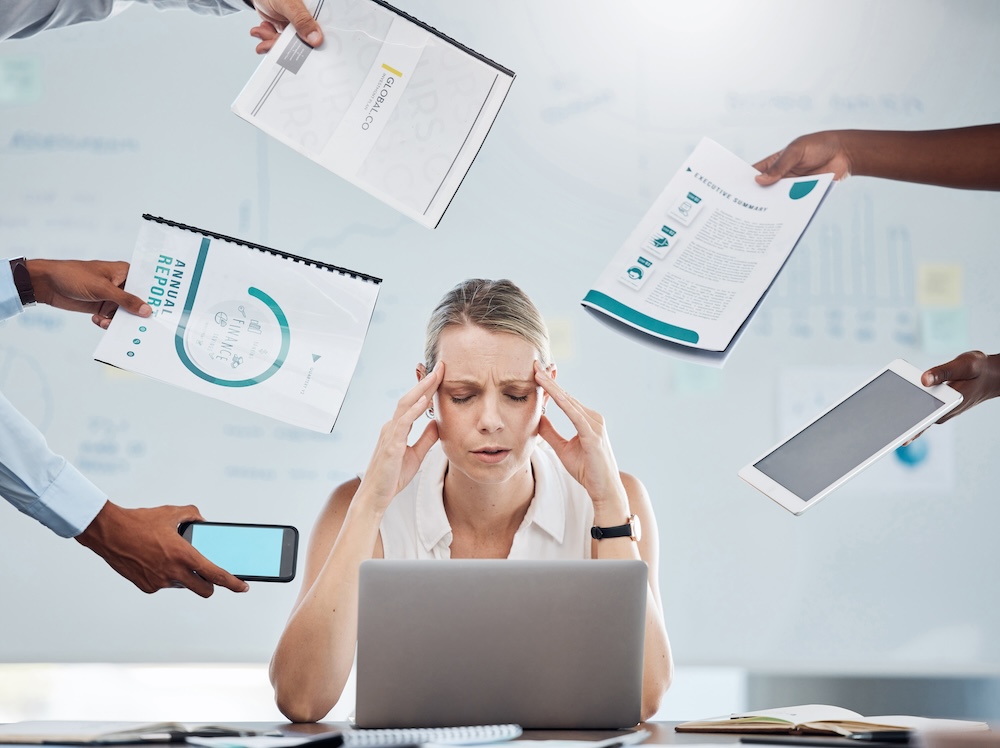 Photo of woman looking stressed out at her laptop because she can't focus on the task at hand, or the additional projects being handed to her. A sign that she needs to seek ADHD treatment in Jacksonville