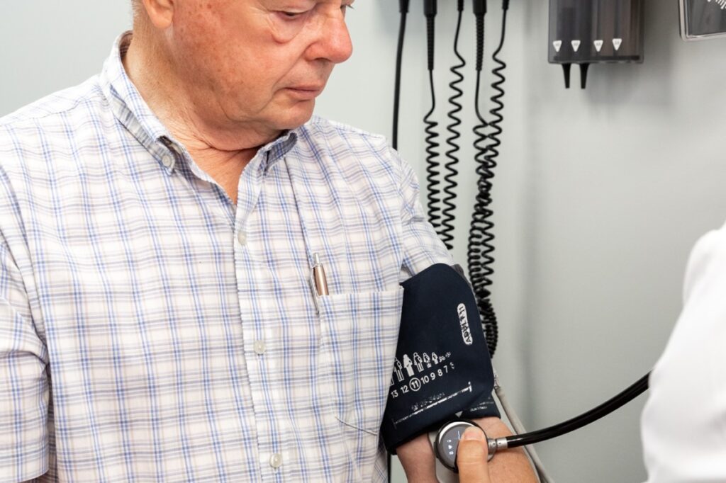 Physician places medical device on patients arm to assess his heart rate and create a personalized heart health treatment plan to prolong the need to see a cardiologist in Jacksonville, NC