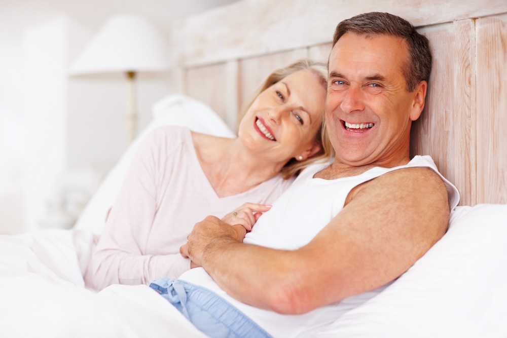 Older couple laying in bed happy that the man went to Coastal Carolina for erectile dysfunction treatment in Jacksonville, NC