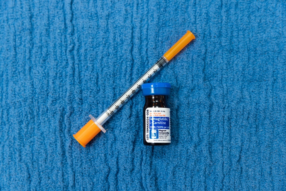 A blue background behind an injection needle and another vial of semaglutide near Swansboro, NC.